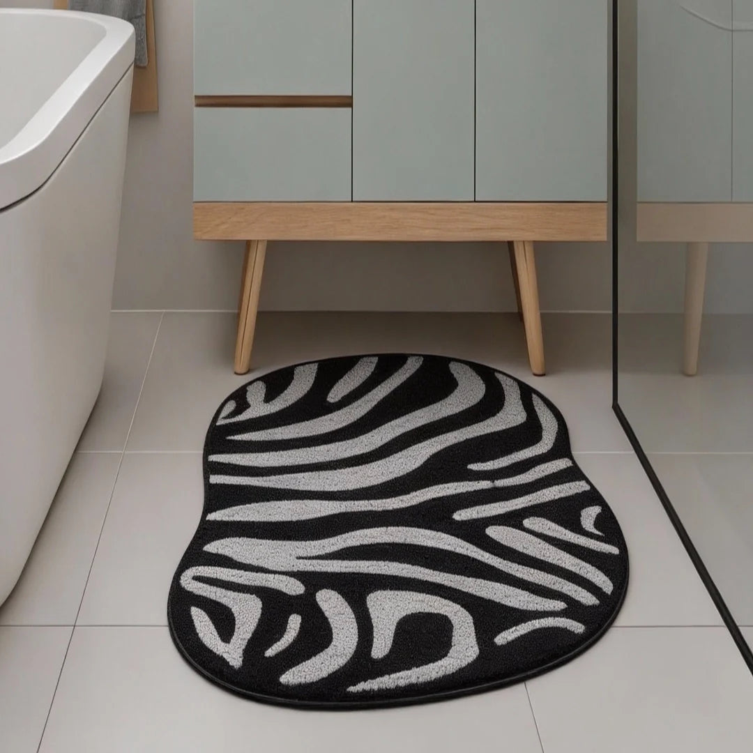 Irregular black and white zebra pattern rug placed in a modern bathroom with a bathtub, vanity, and indoor plants