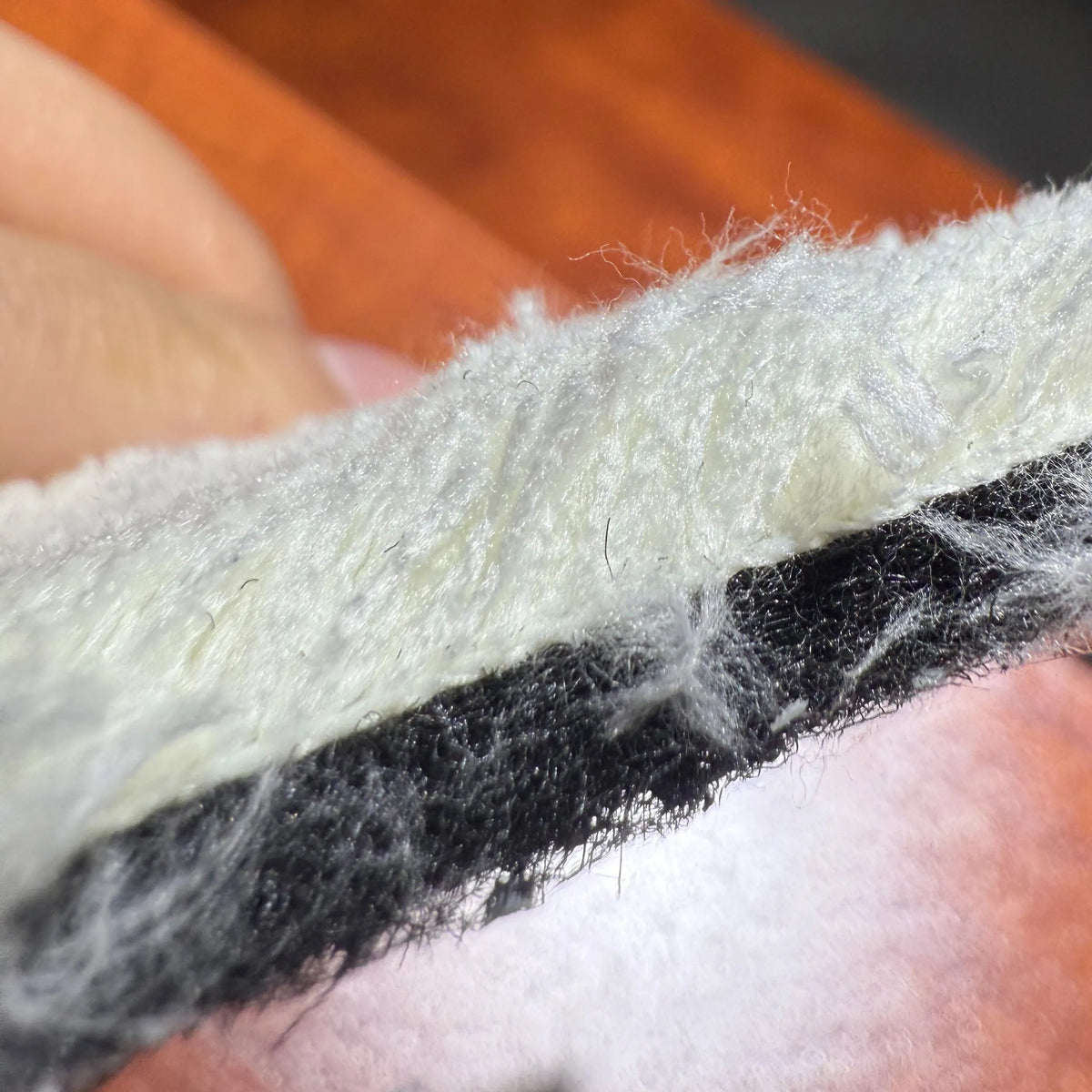 Close-up of a person holding a strip of white and black material, possibly insulation or carpet padding.
