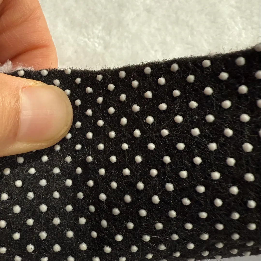 Close-up of the non-slip dotted backing on the 5ft round abstract wave faux cashmere rug from A Print Nest