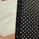 Back edge detail of rug with black overlock stitching and dotted non-slip backing.