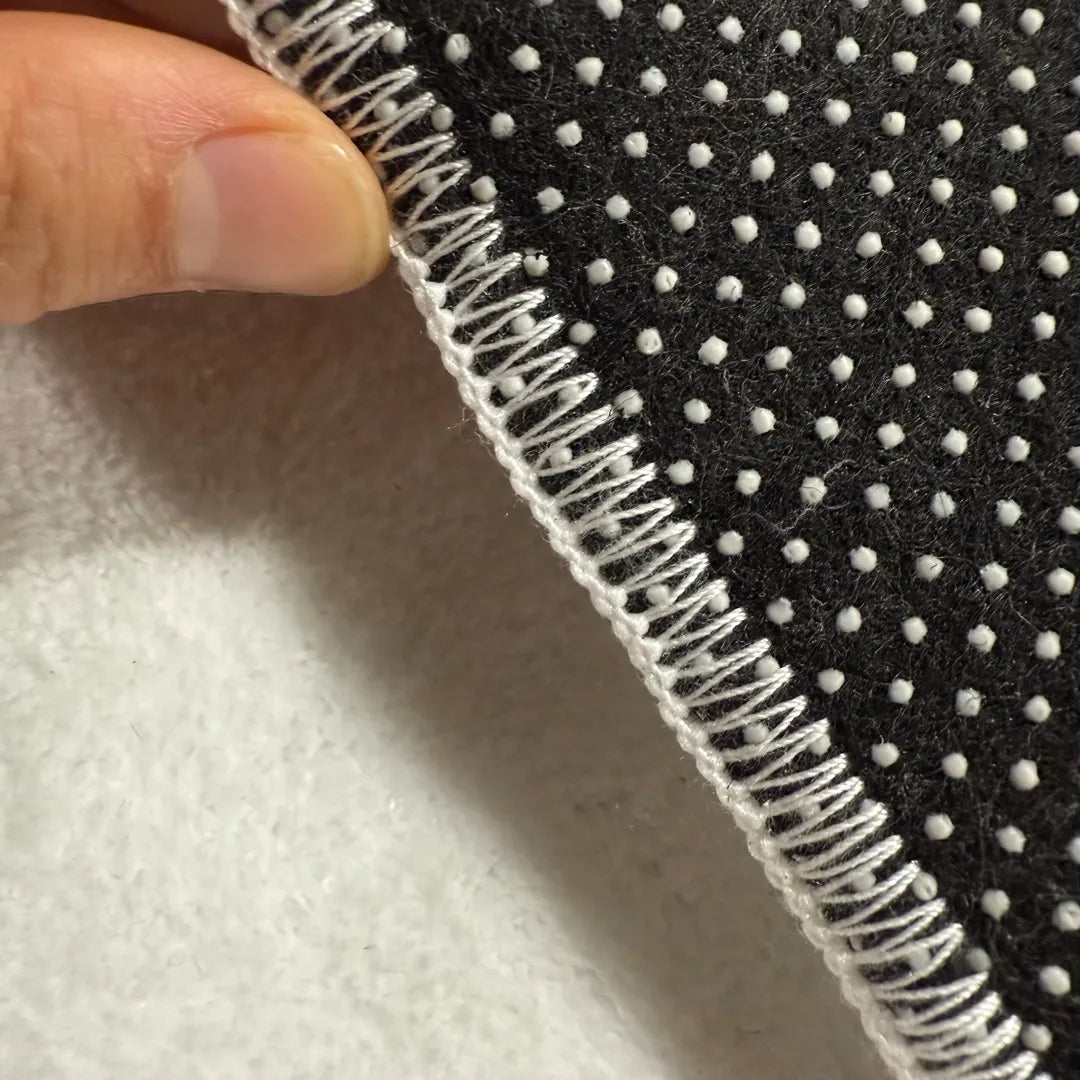 Back edge detail of rug with warm white overlock stitching and dotted non-slip backing.