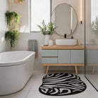 Irregular black and white zebra pattern rug placed in a modern bathroom with a bathtub, vanity, and indoor plants